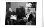 1930s elderly couple sitting in living room listening to radio woman knitting man with newspaper in lap by Anonymous