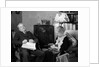 1930s elderly couple sitting in living room listening to radio woman knitting man with newspaper in lap by Anonymous
