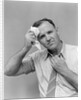1940s 1950s perspiring man in rolled up shirt sleeves loosening tie holding handkerchief wiping forehead looking at camera by Anonymous