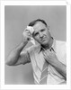 1940s 1950s perspiring man in rolled up shirt sleeves loosening tie holding handkerchief wiping forehead looking at camera by Anonymous