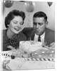1950s 1960s couple with birthday anniversary cake man blowing out candle by Anonymous
