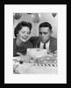 1950s 1960s couple with birthday anniversary cake man blowing out candle by Anonymous
