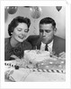 1950s 1960s couple with birthday anniversary cake man blowing out candle by Anonymous