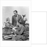 1930s two men one woman golf clubs bag smiling talking sitting bamboo chair man smoking pipe by Anonymous