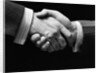 1930s close-up of businessmen's hands in handshake against dark background by Anonymous