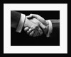 1930s close-up of businessmen's hands in handshake against dark background by Anonymous