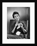 1950s woman crocheting baby sock looking at camera by Anonymous