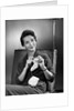 1950s woman crocheting baby sock looking at camera by Anonymous
