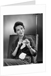 1950s woman crocheting baby sock looking at camera by Anonymous
