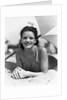 1930s teen girl lying on beach under umbrella wearing bathing suit smiling looking at camera by Anonymous