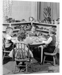 1950s 4 pre-school age children seated at small round table putting together jigsaw puzzle by Anonymous