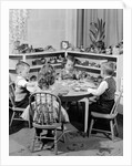 1950s 4 pre-school age children seated at small round table putting together jigsaw puzzle by Anonymous