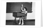 1930s 1940s smiling girl sitting at desk raising her hand by Anonymous