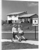 1950s back view of twin girls in plaid skirts & cardigans holding book bags running past school slow sign by Anonymous
