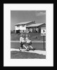 1950s back view of twin girls in plaid skirts & cardigans holding book bags running past school slow sign by Anonymous