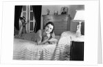 1940s fully dressed smiling woman laying on her bed with her legs up reading a letter in her bedroom by Anonymous
