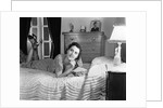 1940s fully dressed smiling woman laying on her bed with her legs up reading a letter in her bedroom by Anonymous