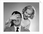 1950s woman standing behind man with hand over his eyes by Anonymous