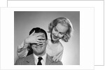 1950s woman standing behind man with hand over his eyes by Anonymous
