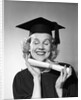 1950s smiling woman teenage girl eyes closed holding diploma graduate wearing cap gown by Anonymous
