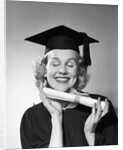 1950s smiling woman teenage girl eyes closed holding diploma graduate wearing cap gown by Anonymous