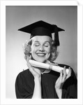 1950s smiling woman teenage girl eyes closed holding diploma graduate wearing cap gown by Anonymous