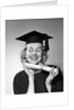 1950s smiling woman teenage girl eyes closed holding diploma graduate wearing cap gown by Anonymous