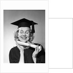 1950s smiling woman teenage girl eyes closed holding diploma graduate wearing cap gown by Anonymous