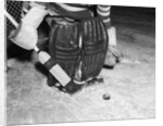 1940s 1950s close-up of padded goalie shown waist-down holding stick with puck in front of him by Anonymous