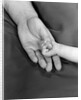 1950s close-up of baby holding mother's thumb by Anonymous