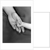 1950s close-up of baby holding mother's thumb by Anonymous
