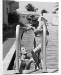 1930s woman wearing one piece bathing suit climbing out of swimming pool looking down at man smiling by Anonymous