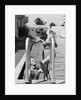 1930s woman wearing one piece bathing suit climbing out of swimming pool looking down at man smiling by Anonymous