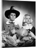 1950s boy & girl in pilgrim costumes with harvest arrangement on table by Anonymous
