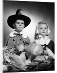 1950s boy & girl in pilgrim costumes with harvest arrangement on table by Anonymous