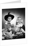 1950s boy & girl in pilgrim costumes with harvest arrangement on table by Anonymous