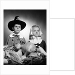 1950s boy & girl in pilgrim costumes with harvest arrangement on table by Anonymous