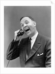 1930s man in suit laughing talking on telephone by Anonymous