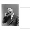 1930s man in suit laughing talking on telephone by Anonymous