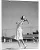 1930s woman playing tennis about to hit ball with racket by Anonymous
