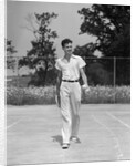 1930s man walking across tennis court holding tennis racket & balls by Anonymous