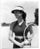 1930s woman in polka dot halter top shorts & sun visor holding a tennis ball & racket by Anonymous