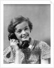 1930s teen girl smiling brunette print dress talking on telephone by Anonymous