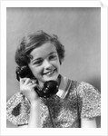 1930s teen girl smiling brunette print dress talking on telephone by Anonymous