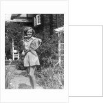 1930s teen girl brunette on sidewalk of house holding tennis racket wearing shorts by Anonymous