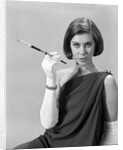 1960s formally elegantly dressed young woman looking at camera with a cigarette holder wearing long white gloves by Anonymous