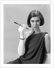 1960s formally elegantly dressed young woman looking at camera with a cigarette holder wearing long white gloves by Anonymous