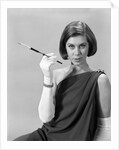1960s formally elegantly dressed young woman looking at camera with a cigarette holder wearing long white gloves by Anonymous