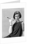 1960s formally elegantly dressed young woman looking at camera with a cigarette holder wearing long white gloves by Anonymous