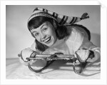 1950s smiling young teenage woman posing on sled in winter wool knit clothes looking at camera by Anonymous